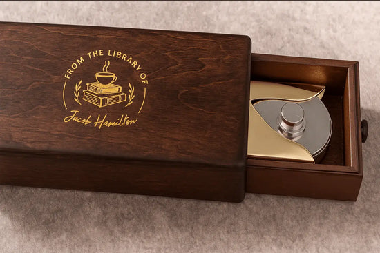 Wooden box with a engraved message and a silver object inside on a gray surface